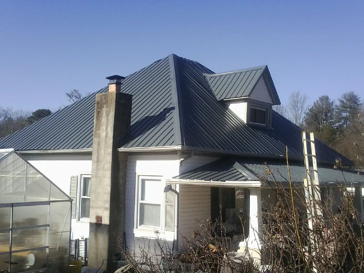 Dark blue standing seam metal roof on a white farmhouse with dormer — Slate & Tile Roof Repair by Roofing Brothers in Murrysville