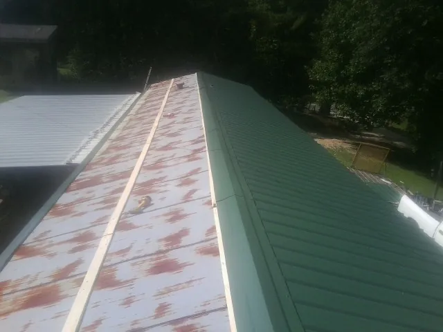 Old rusted panels beside newly installed green metal roofing — Wind Damage Roof Repair by Roofing Brothers in Murrysville