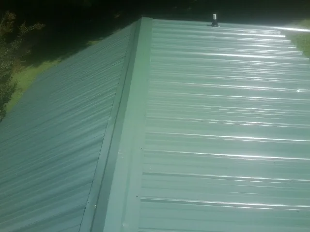 New green metal panels meeting at the ridge of a roof — Flat Roof Repair work by our crew in Murrysville