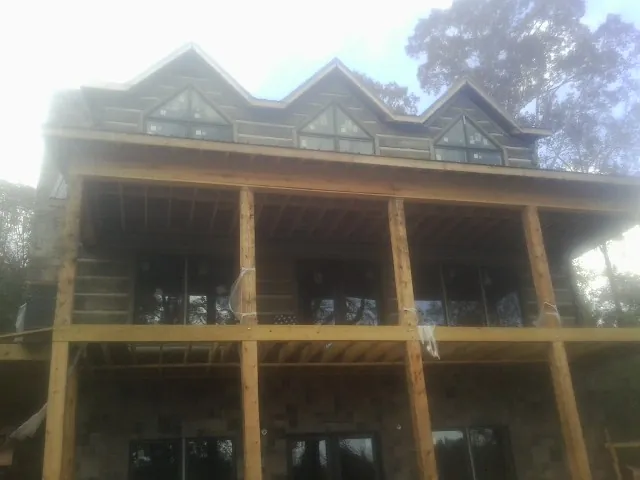 Dormers and porch framing on a large log home under construction — Roof Coating work by our crew in Murrysville