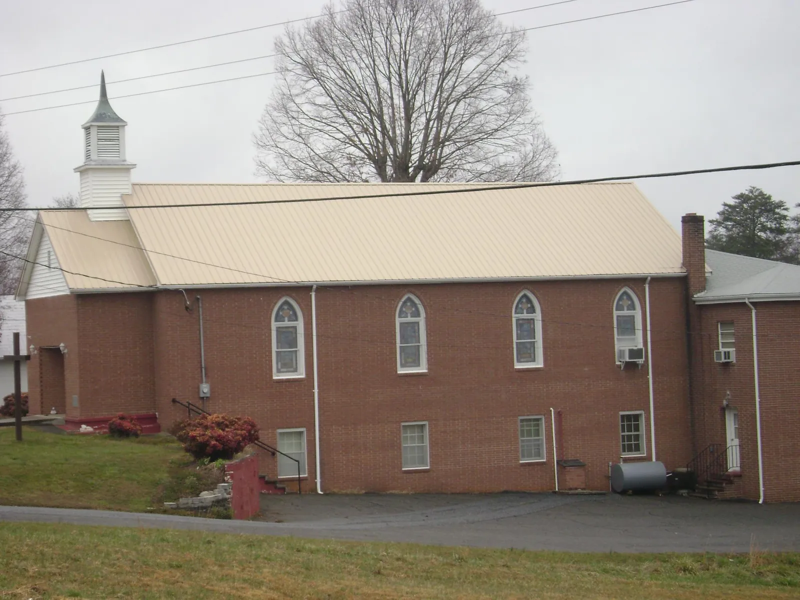 New tan metal roof on a brick church with a white steeple in Murrysville