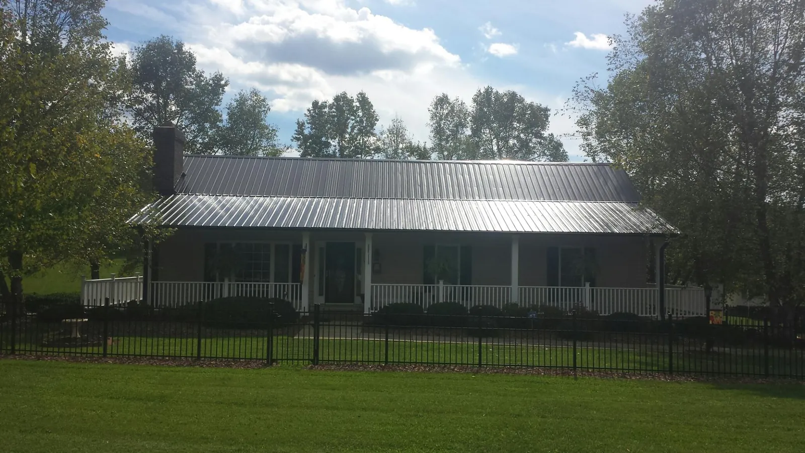 Gray metal roof on a brick ranch with a full width front porch — Gutter Guard Installation work by our crew in Murrysville