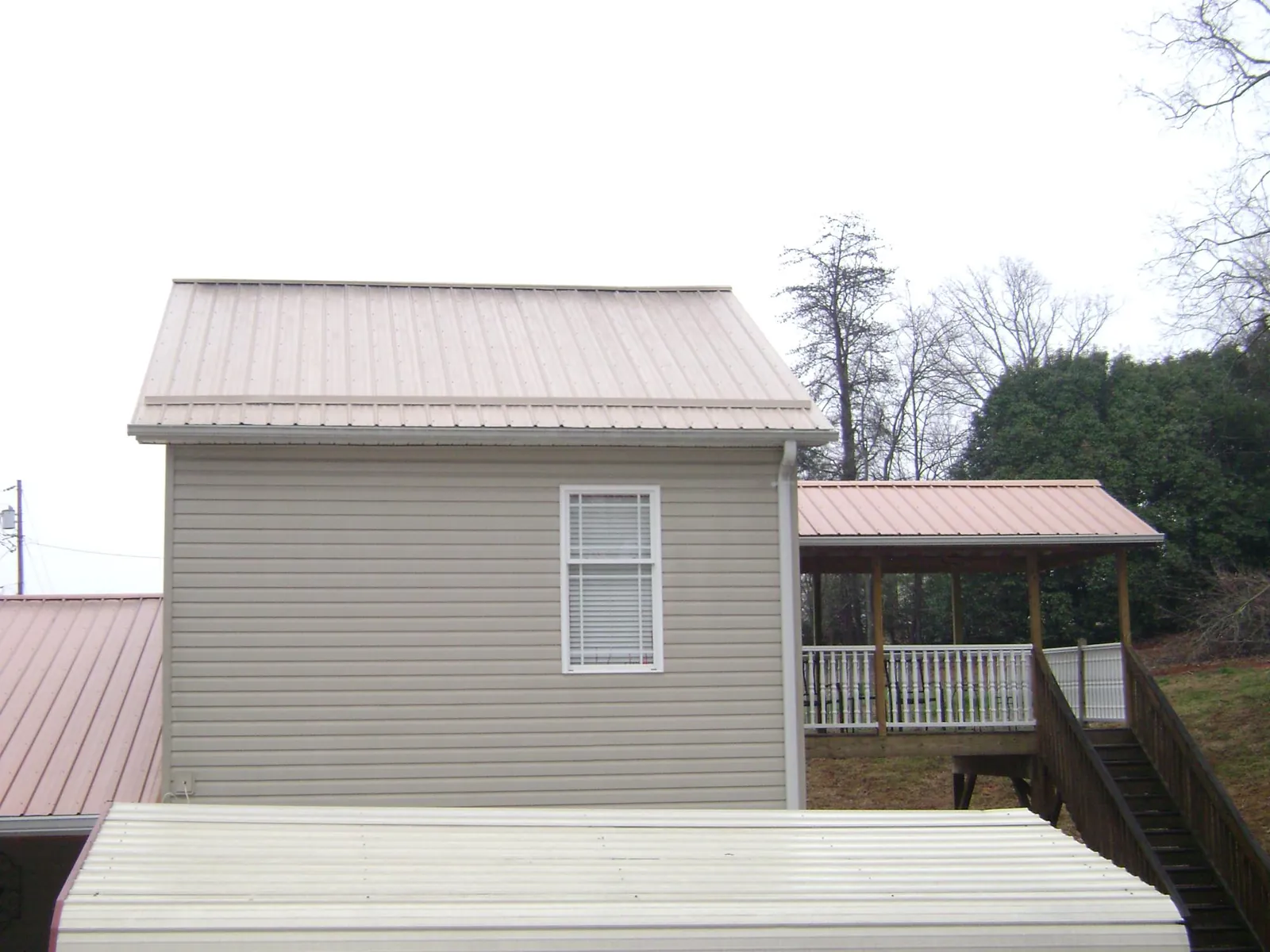 Tan metal roofs on a two story addition and attached porch, from a Roof Replacement job in Murrysville