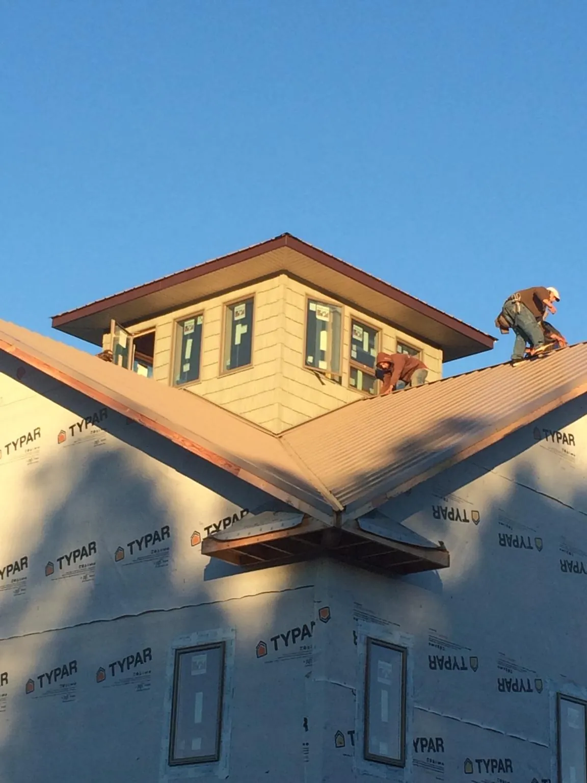 Roofers working around a rooftop cupola on a new metal roof at sunset — Roof Waterproofing in Murrysville by Roofing Brothers